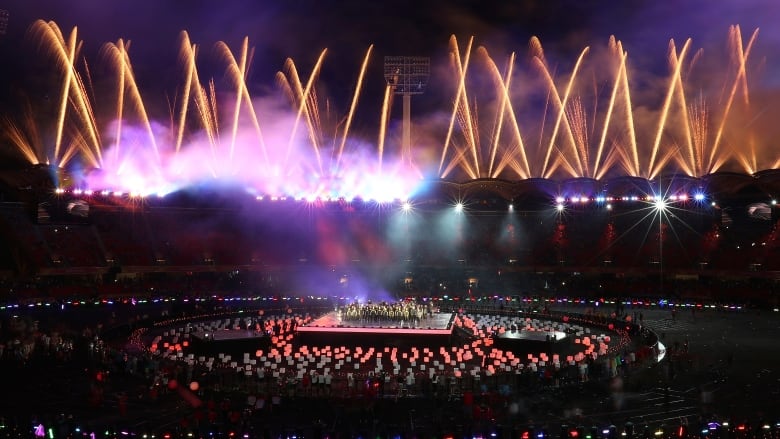 Fireworks go off above a stadium at night.