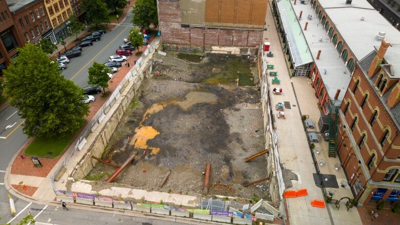 Drone picture of an empty lot with a giant hole in the ground waiting for construction.