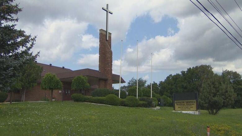 A large cross sits atop a brick church building.