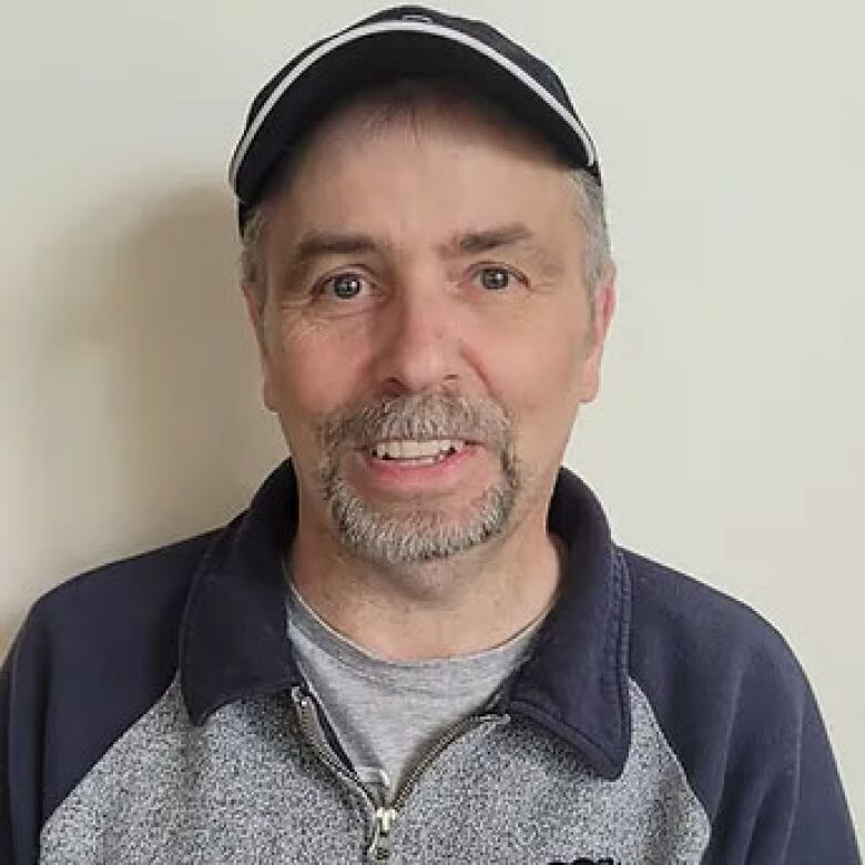 A smiling man wearing a baseball hat.