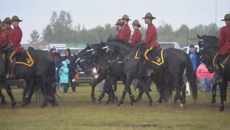 RCMP officers ride their horses in rain.