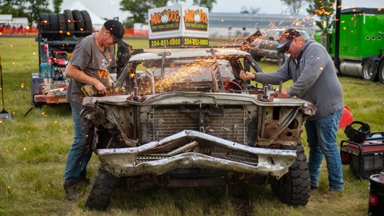 A man uses a grinder on a derby vehcile.