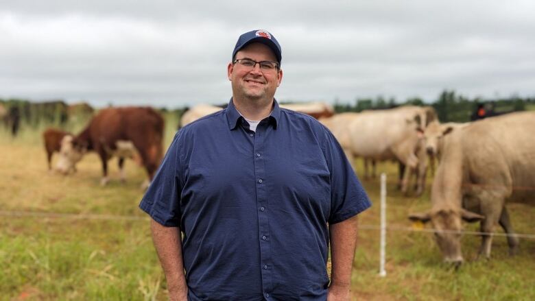 A man stands in front of a herd of beef cows 