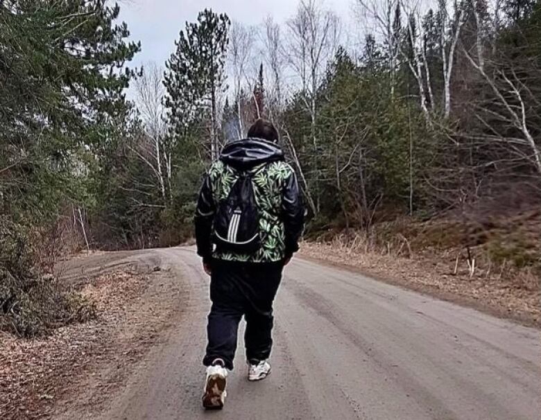 A man walking in a path in the woods.