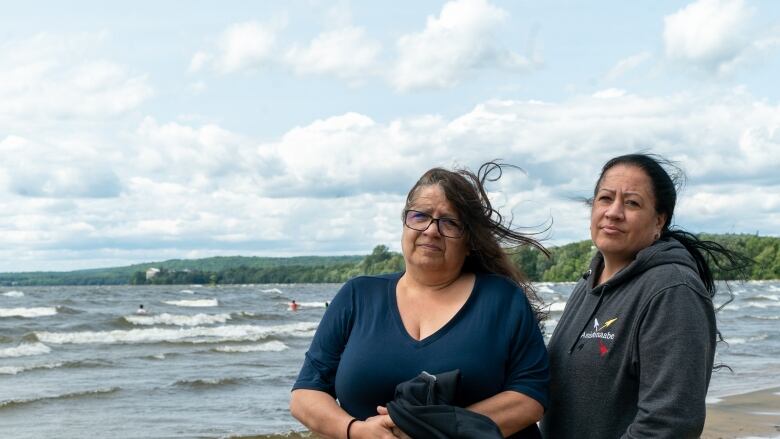 Two women standing in front of a lake.