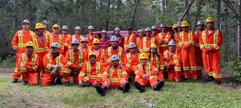 A group of Cree trainees dressed in orange coveralls.