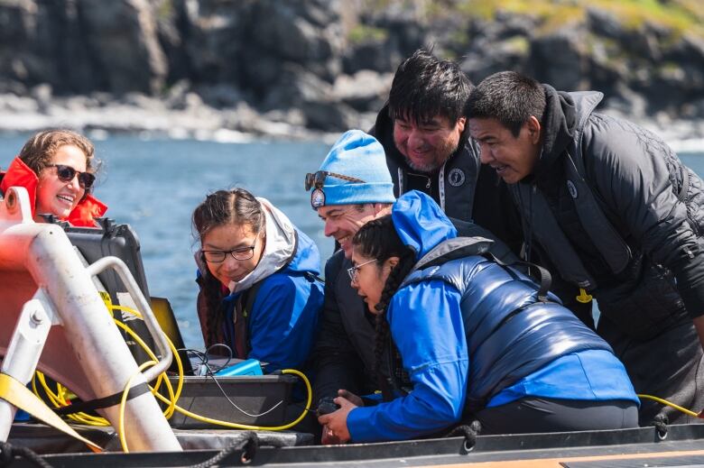 A group of people smile at a computer in a water-proof case. 