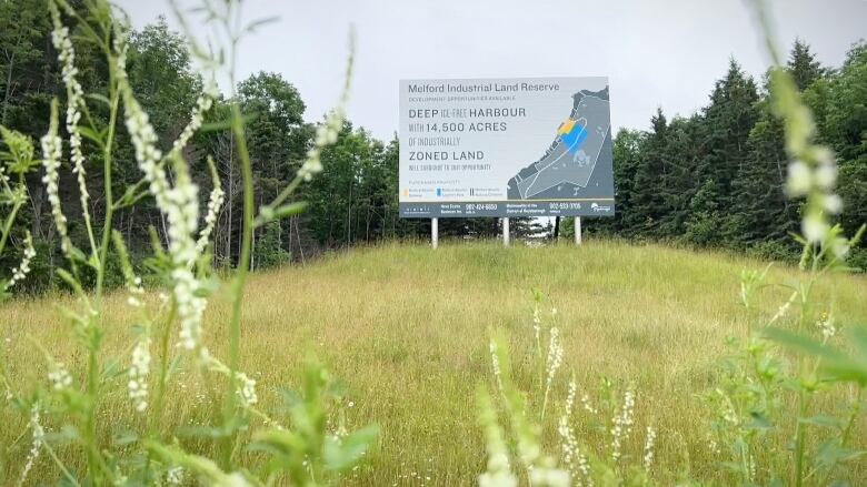 A sign that says 'Melford Industrial Land Reserve' is shown in a field with trees in the background.