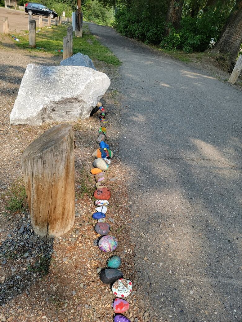 Hand-painted rocks are shown, lined up to form the body of a snake.