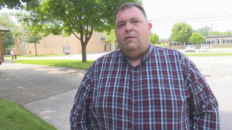 Elton Robinson stands with a street and school behind him