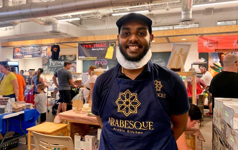 A man wearing a dark blue apron that reads 