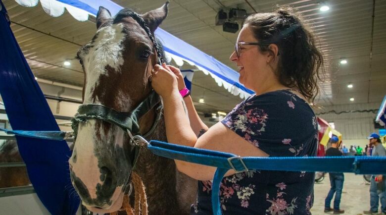 A woman braids a horses mane.