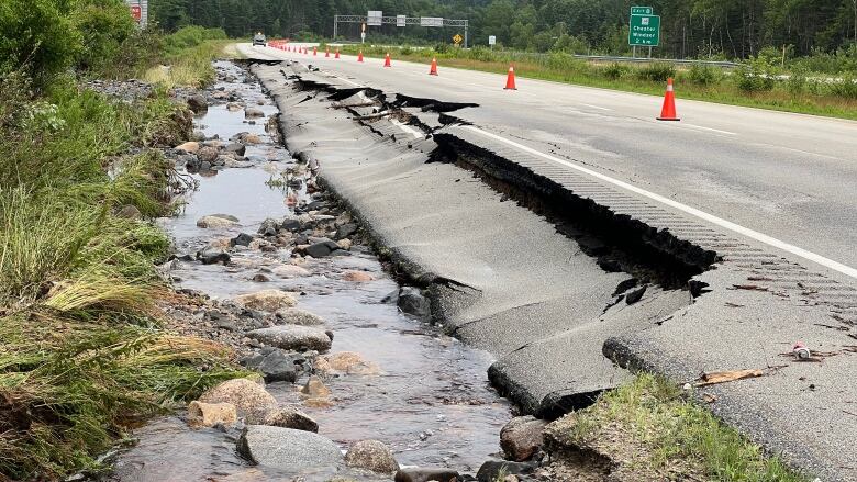 A crumbling section of a highway that has been marked off by pylons.