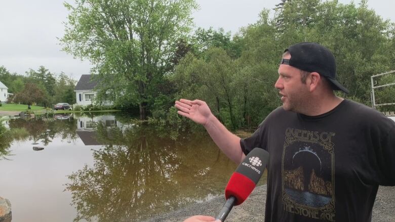 A man pointing out of a field flooded with water in between homes. 