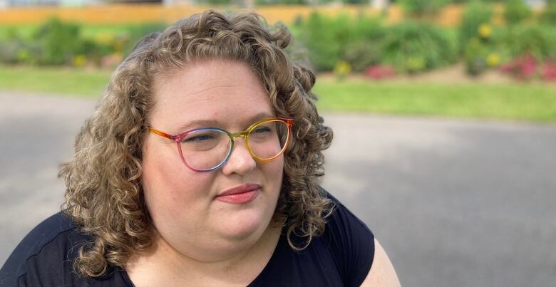 A head and shoulders shot of a woman with curly hair and glasses. 