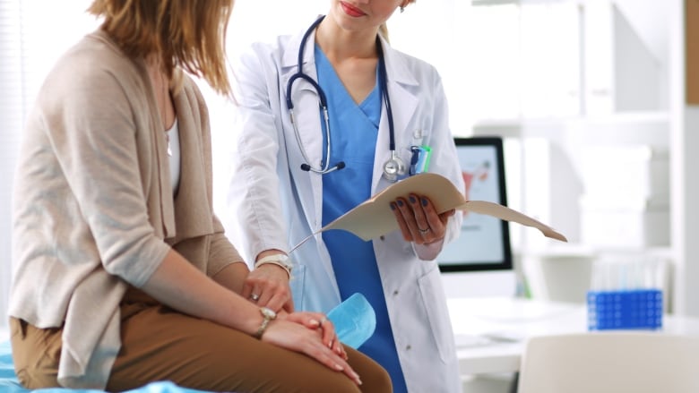 A doctor discusses something with a patient. Doctor holds patients hand in comfort.