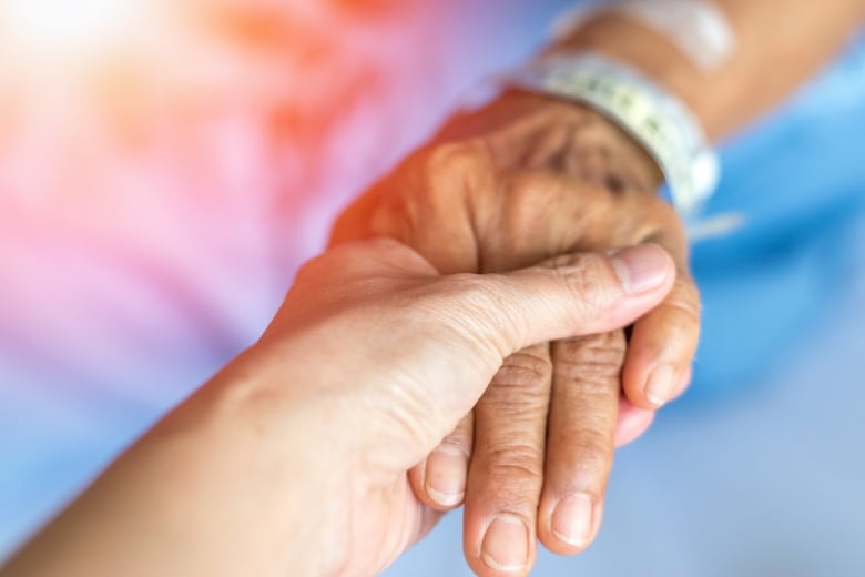 Doctor holds the hand of an older patient.