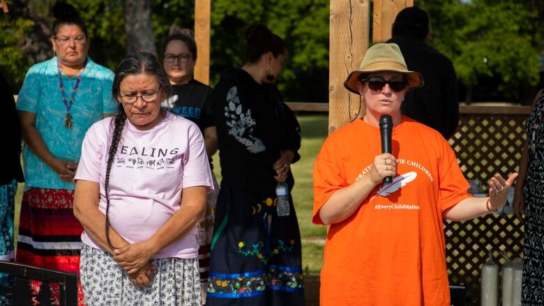 Two women stand together giving a speech.