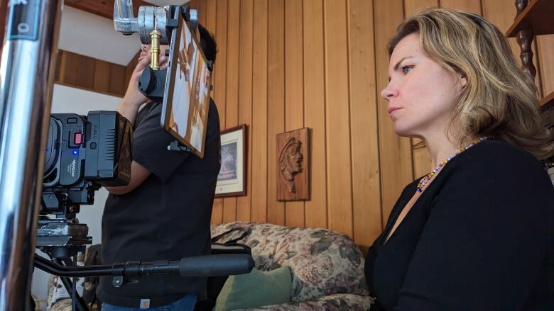 A woman in profile looks at the screen of a digital film camera. 