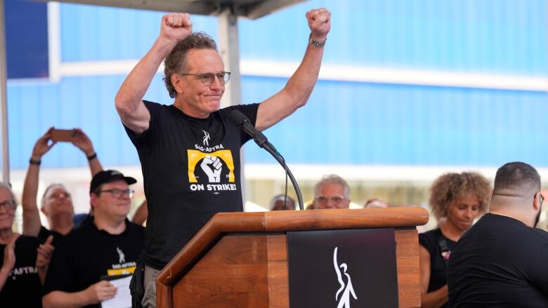 A man standing at a podium raises his fists in the air.