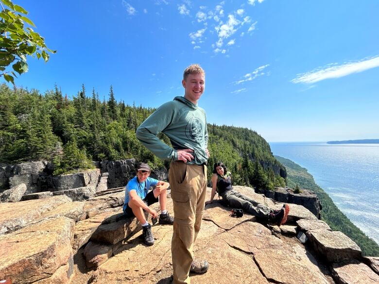 Three campers smile at the camera as they stand on a lookout ledge at Sleeping Giant Provincial Park.