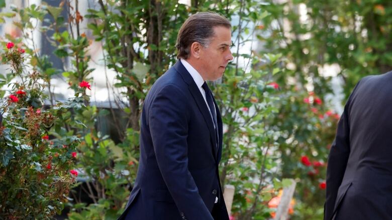 A man in a suit is shown in profile walking outside.