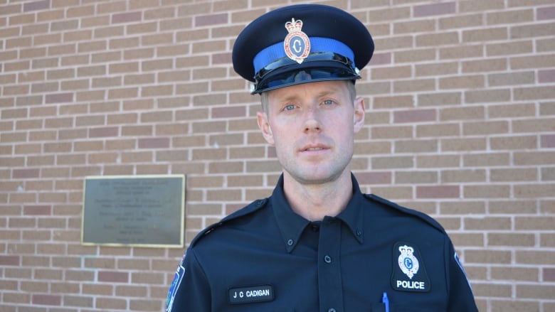 A man in police uniform against brick wall