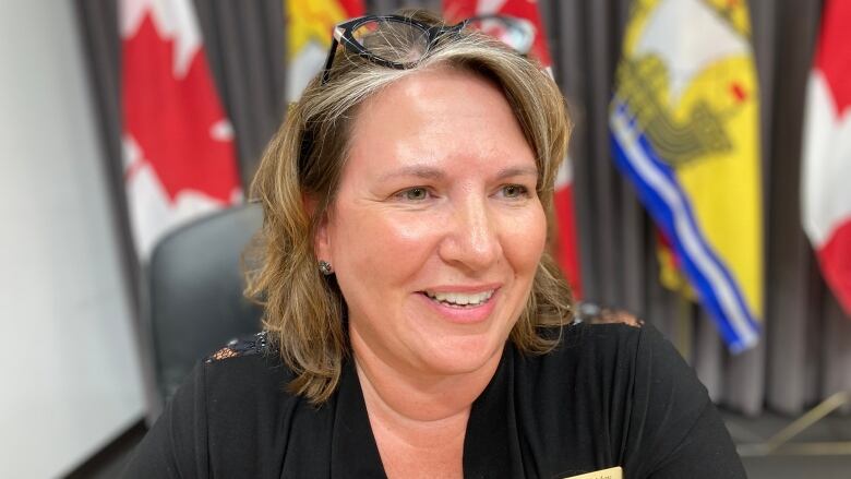 Medium shot of woman smiling, flags in the background