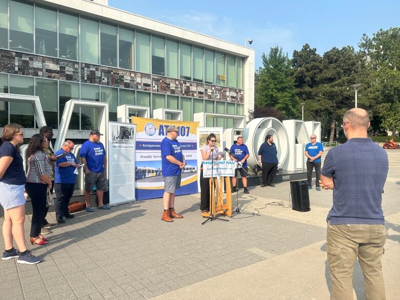 Person watching speaker at podium in front of Hamilton city hall