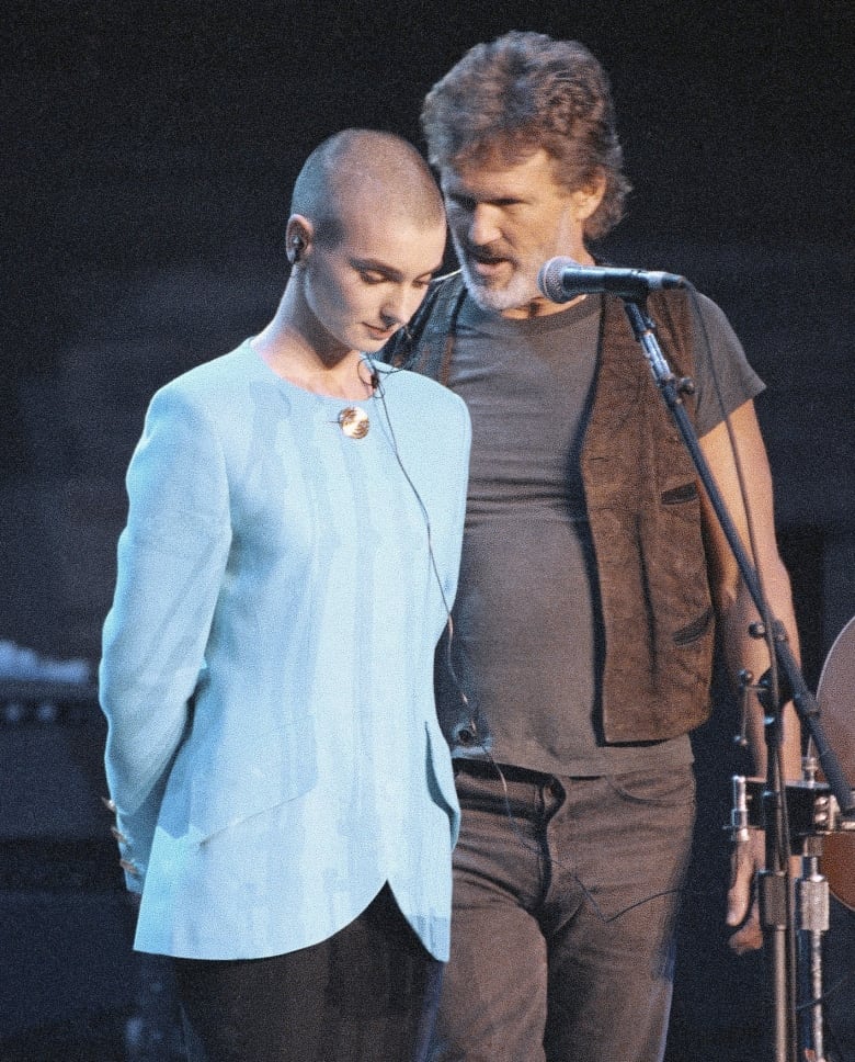 A man speaks to a young woman while they are on a performance stage.