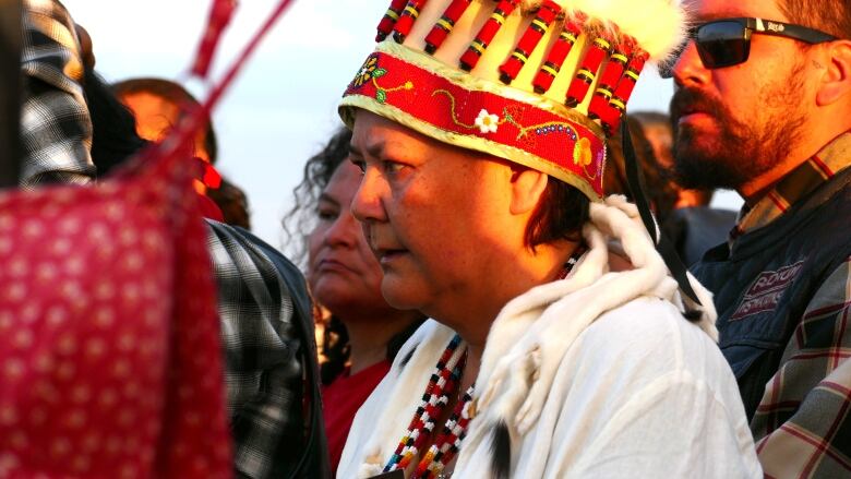 Woman in ceremonial garb looks intently in a crowd of people.