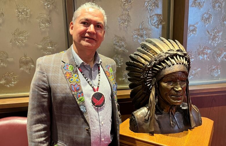 A man in a suit beside a statue.