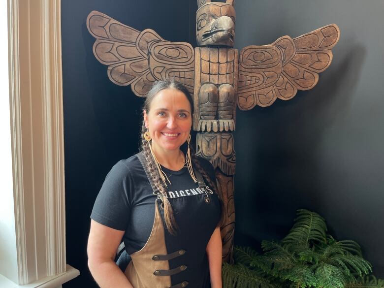 Woman standing in front of totem pole.