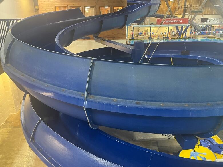 A picture of a big blue water slide that over hands the pool deck at the Aquarena