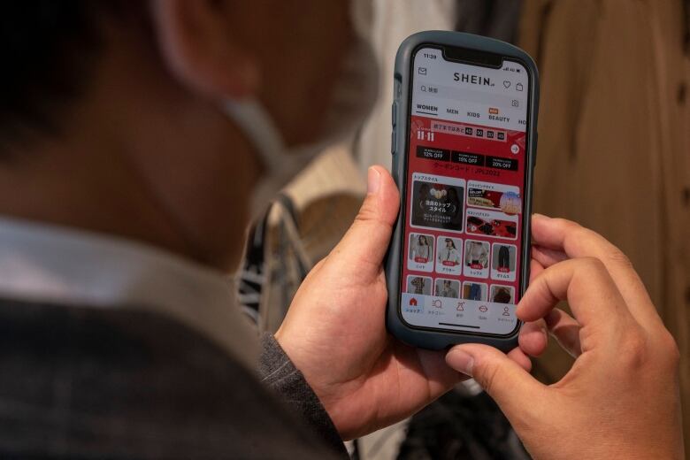 A man looking at the Shein shopping app on a mobile phone.