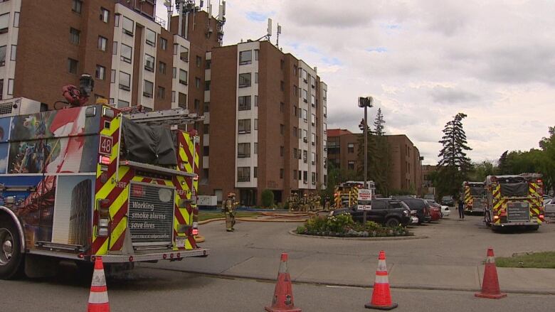 Fire trucks sit in front of a tall building. 