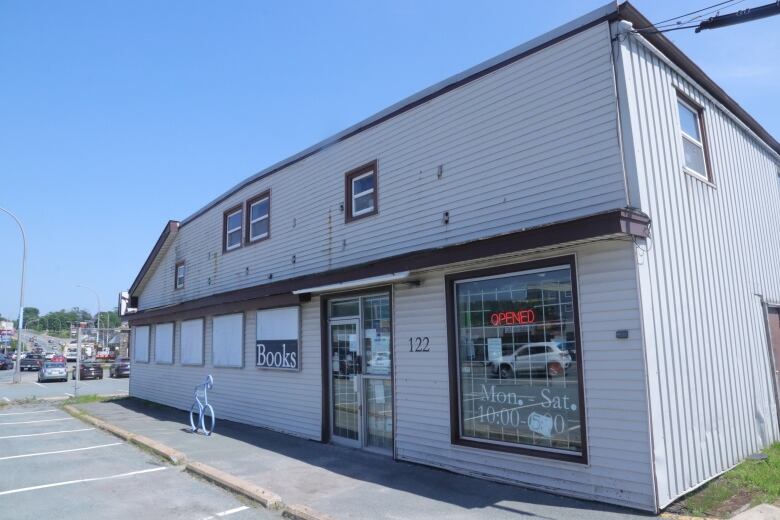 A white building, with vinyl siding, that houses John W Doull's book store.