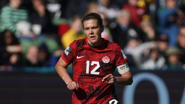 A soccer player in a red No. 12 jersey runs.