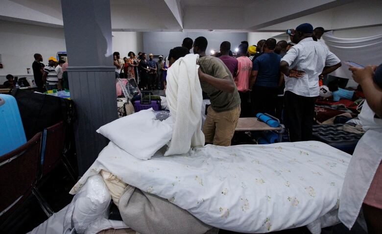 A resident of RevivaltimeTabernacle, where more than 200 mostly African migrants have been sleeping, adjusts his bedding during a visit by Toronto Mayor Olivia Chow.