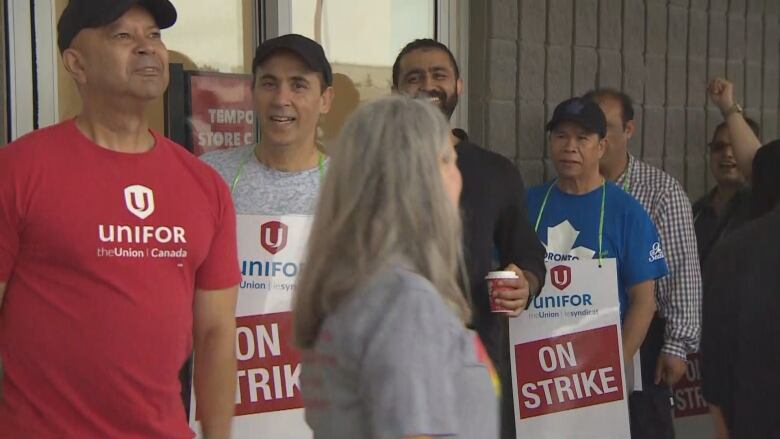 Metro workers stand outside of the grocery store at 3003 Danforth Avenue after going on strike Saturday.