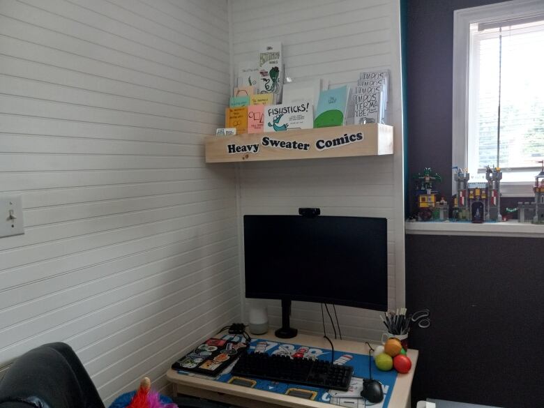 A desk with a shelf floating above it filled with comics and a sign saying 