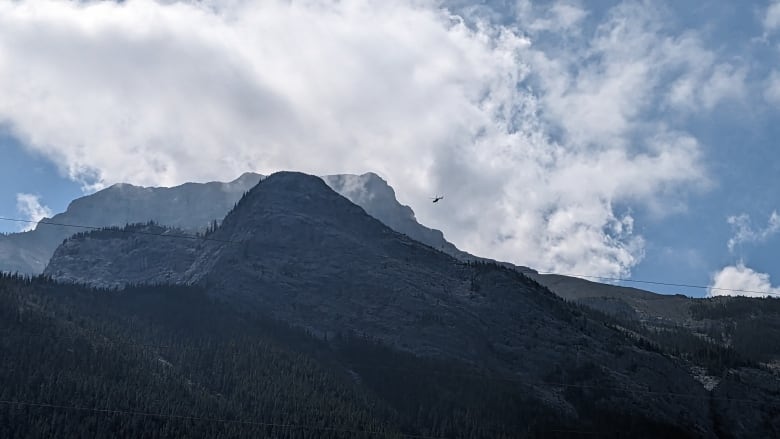 A helicopter flies near Mount Bogart in Kananaskis Country on July 29, 2023, following a plane crash that left six people dead. 