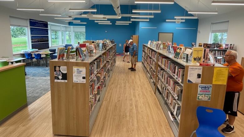 People look at books and different shelves inside the library. 