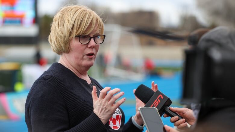 A woman speaks to media reporters.