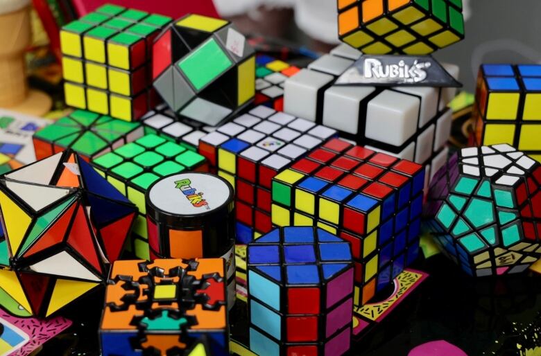 A group of multi-coloured Rubik's Cubes and similar items on a table.