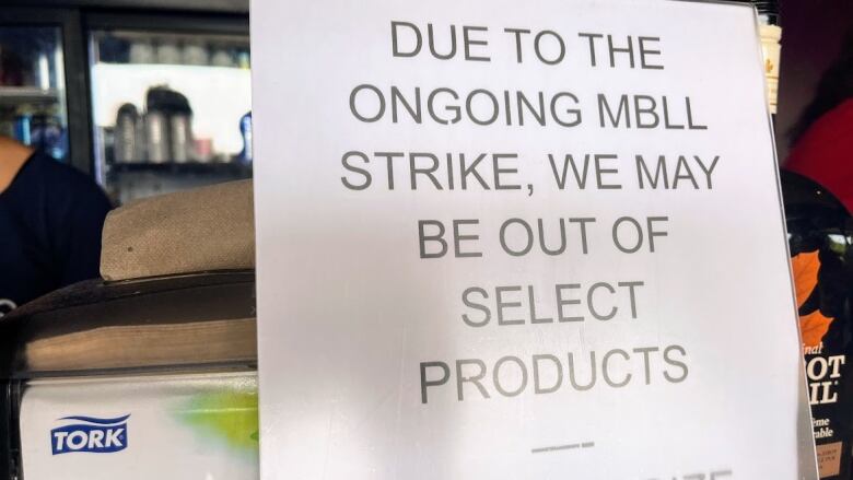 A closeup of a sign says that, due to the ongoing liquor and lotteries strike, some products might not be available.