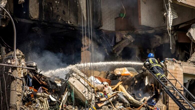 A firefighter hoses down a badly damaged apartment building.