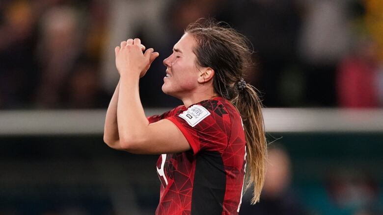 A woman soccer player reacts with disappointment after a loss.