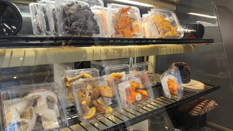 A fridge with several varieties of packaged wild mushrooms. 