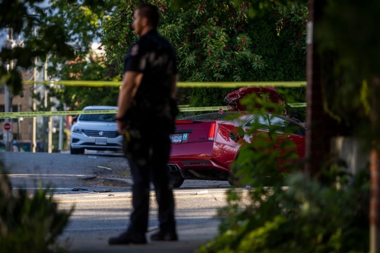 Police officer stands in front of cars involved in a collision. 